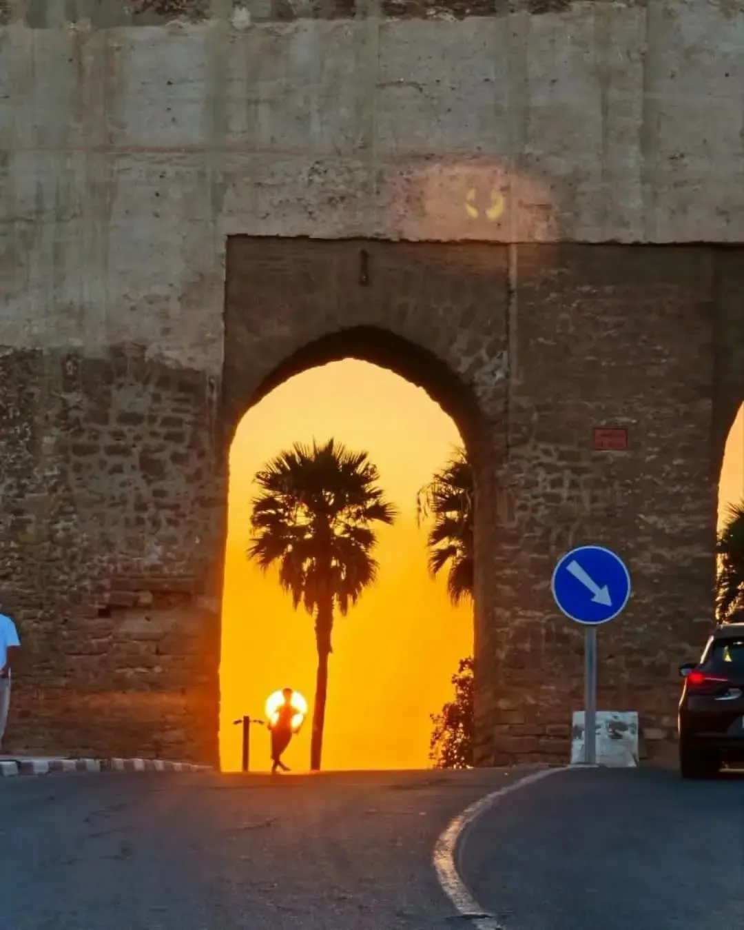 Une porte des remparts de Safi encadre un palmier et le soleil couchant.